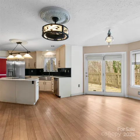 a large kitchen with stainless steel appliances a large counter top a stove and a wooden floors
