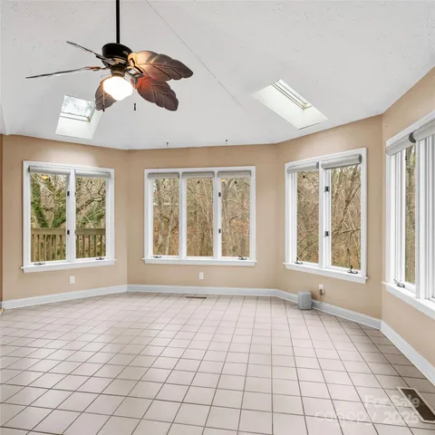 a view of an empty room with a window and chandelier fan