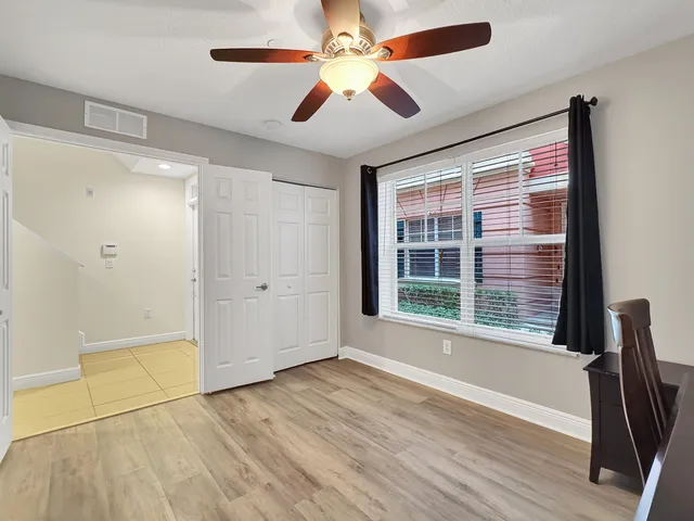 a view of an empty room with a window and wooden floor