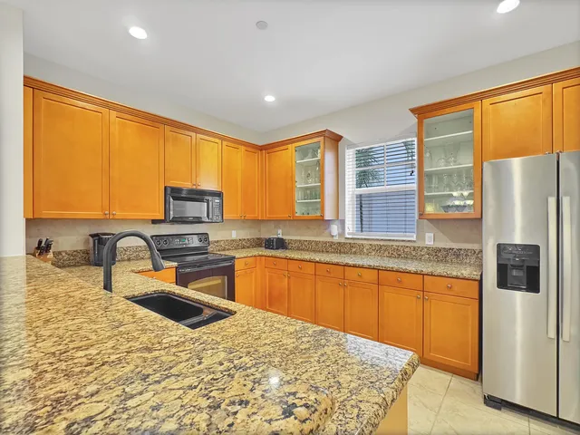 a kitchen with stainless steel appliances granite countertop a sink refrigerator stove and a granite counter top