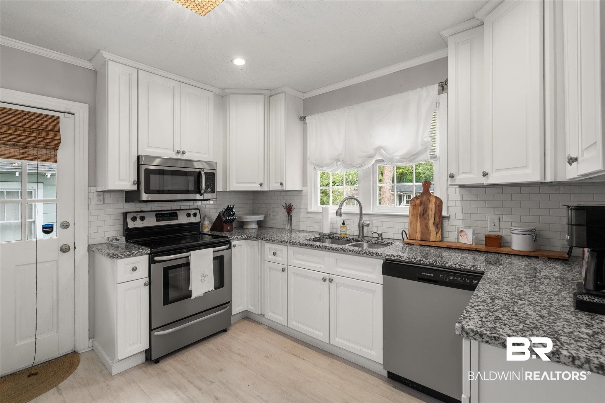 165 Crenshaw Street Mobile, AL 36606 - Photo 6 of 21 Kitchen featuring appliances with stainless steel finishes, ornamental molding, white cabinetry, backsplash, and stone counters