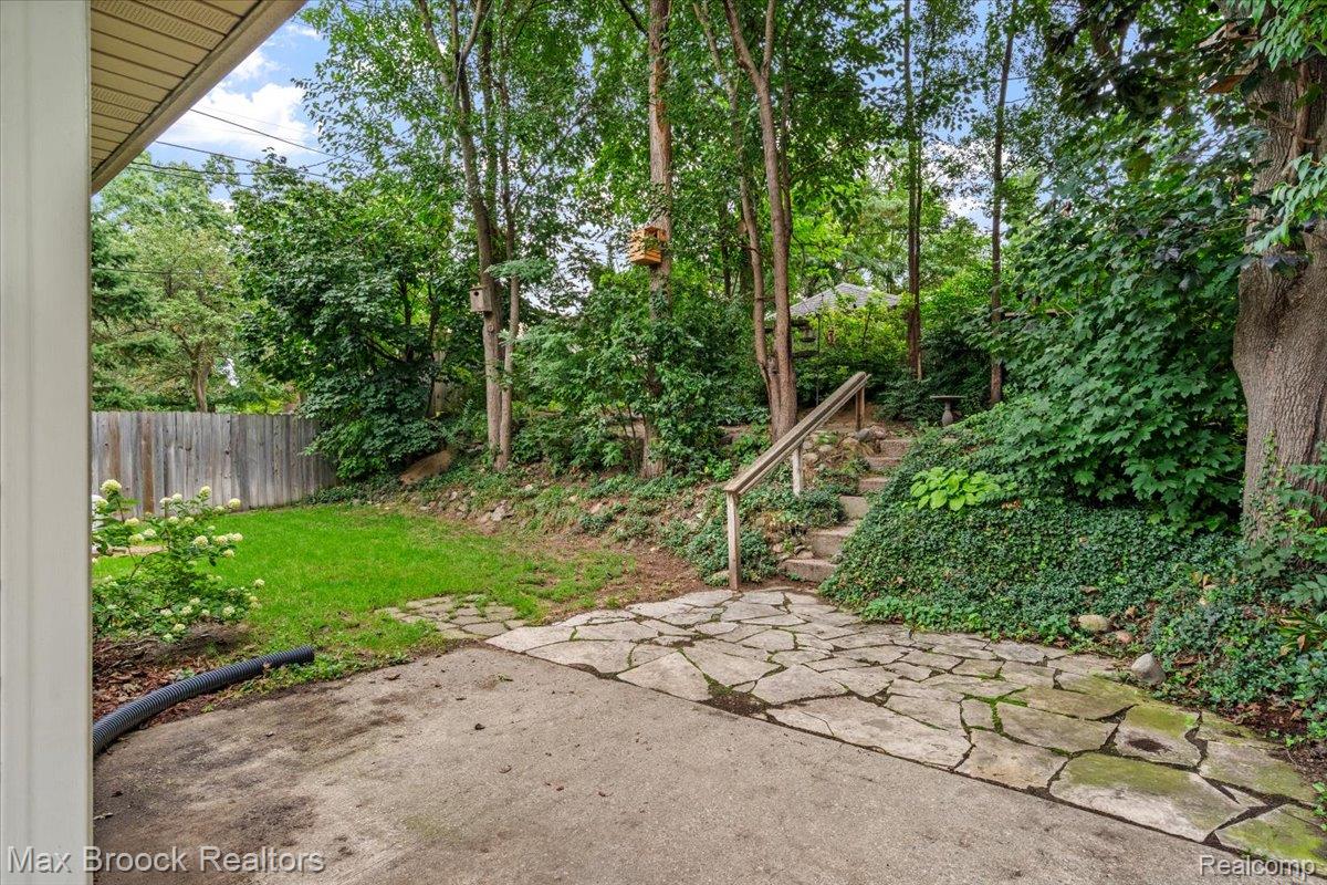 1330 Oak Street Rochester, MI 48307 - Photo 24 of 35 Expansive backyard featuring a partial wood fence, concrete patio, stone steps with handrails, and mature trees