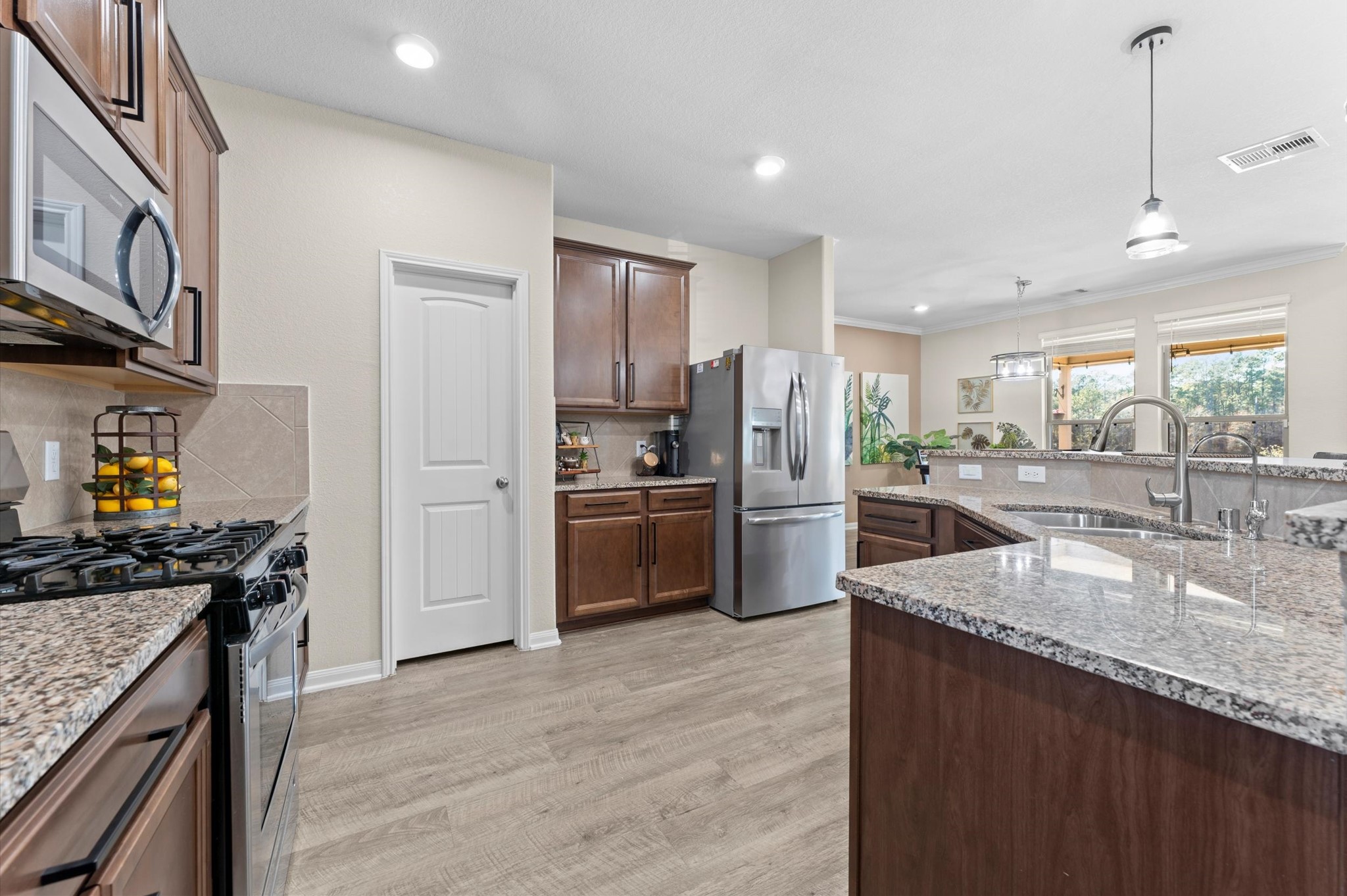 9729 Hidalgo Street Conroe, TX 77303 - Photo 16 of 38 Modern kitchen with stainless steel appliances, granite countertops, and wooden cabinetry. Open layout with ample natural light and a view into the living area. Perfect for entertaining and daily family use.