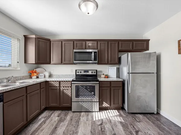 a kitchen with stainless steel appliances granite countertop a refrigerator stove a sink dishwasher and a microwave oven on the wooden floor