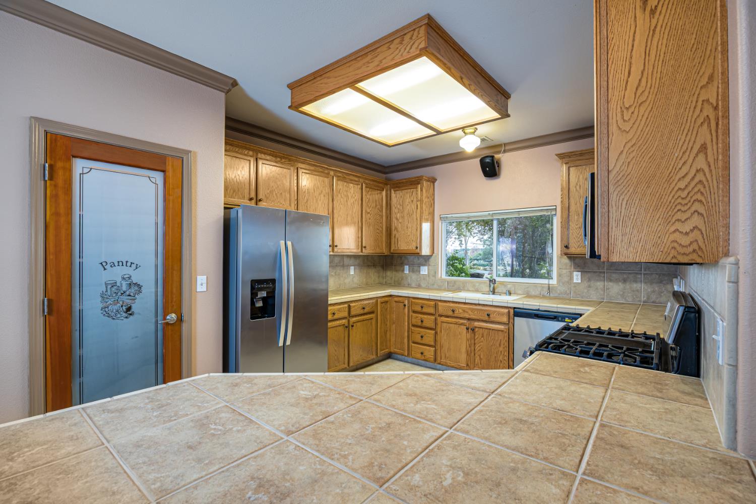 2083 State Rte 26 Valley Springs, CA 95252 - Photo 13 of 59 a kitchen with stainless steel appliances granite countertop a refrigerator a sink dishwasher a stove with wooden cabinets and floor