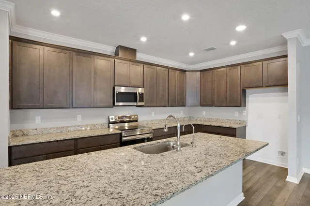 a kitchen with stainless steel appliances granite countertop a sink refrigerator and cabinets