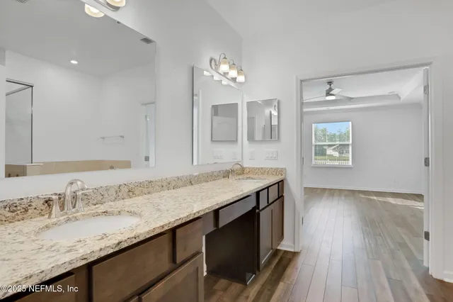 a bathroom with a granite countertop sink a light fixture and a mirror