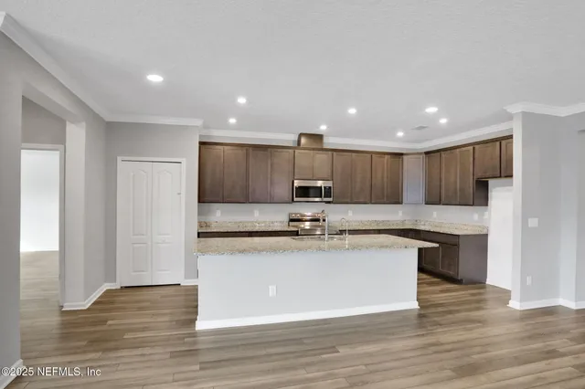 a view of kitchen with stainless steel appliances granite countertop refrigerator stove top oven and cabinets