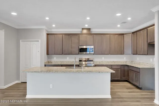 a view of a kitchen with kitchen island sink stainless steel appliances and cabinets