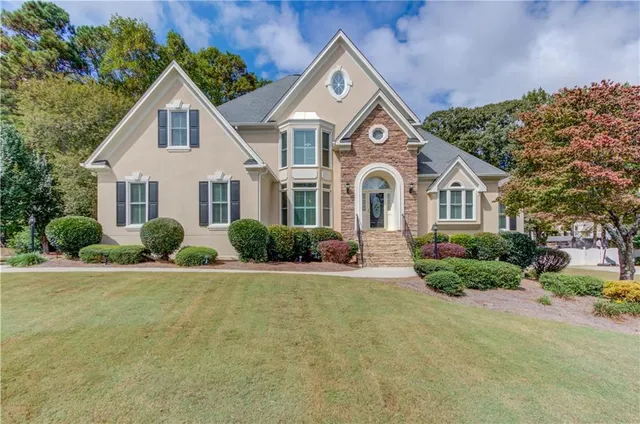 a view of a white house with a big yard and potted plants