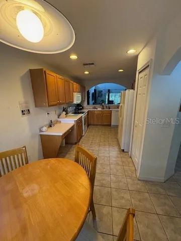 a view of a kitchen with kitchen island a sink stainless steel appliances wooden floor and a counter top space