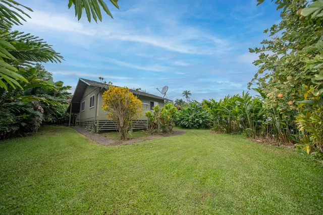 a view of a chairs and table in the patio next to a yard