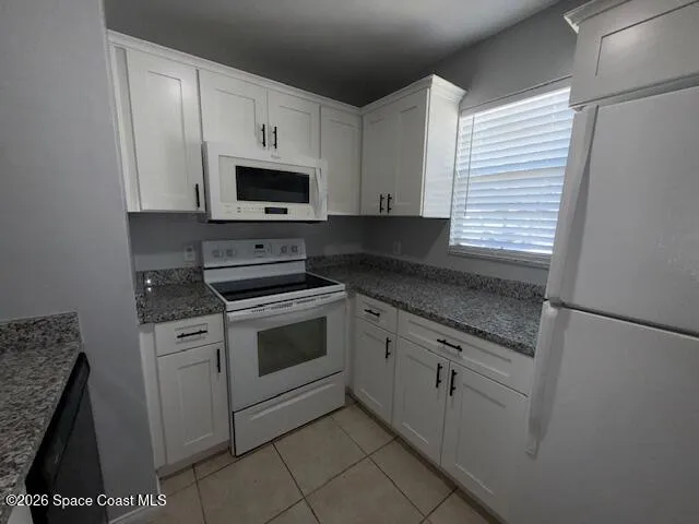 a kitchen with granite countertop white cabinets and black appliances