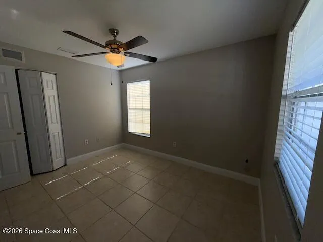 an empty room with windows and a fan