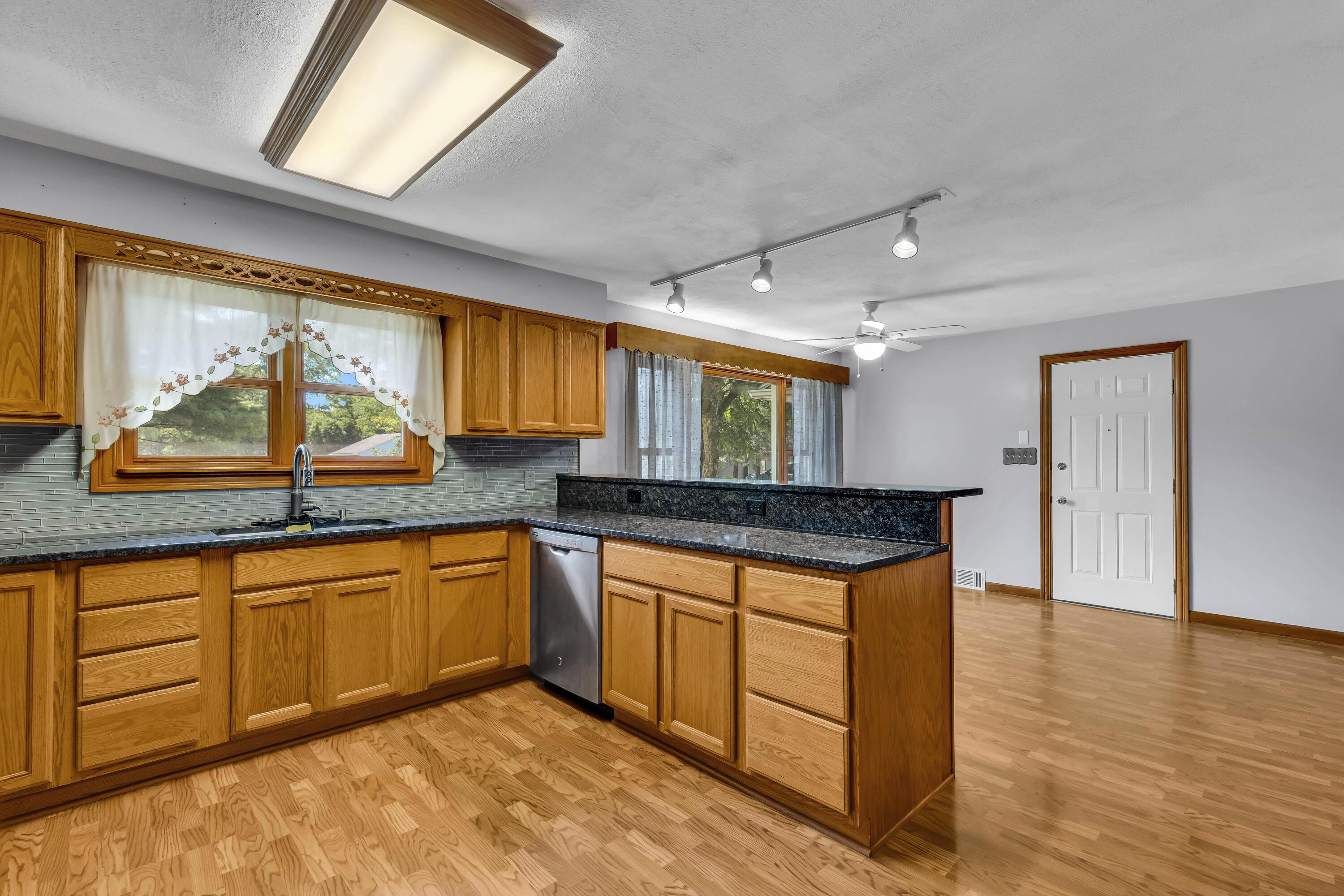 1213 East Cooke Road Columbus, OH 43224 - Photo 22 of 57 • Laminate flooring • Tan painted walls • Oak cabinets • New granite countertops ~ 2020 • Breakfast bar ledge • Track lighting • Kenmore® refrigerator • Tappan® microwave • General Electric® gas stove • New General Electric dishwasher ~ 2020 • Insinkerator® disposal • Glass tile backsplash • Single bowl, stainless steel sink with soap dispenser • Ceiling light • Pantry closet