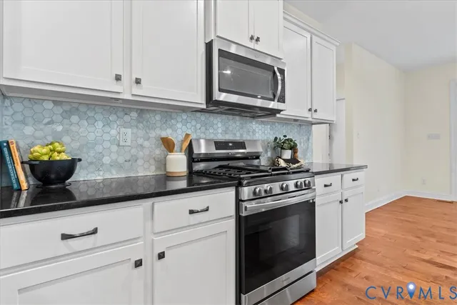 a kitchen with stainless steel appliances granite countertop grey cabinets a stove a sink and dishwasher