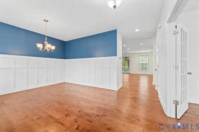 a view of a hallway with wooden floor and a chandelier