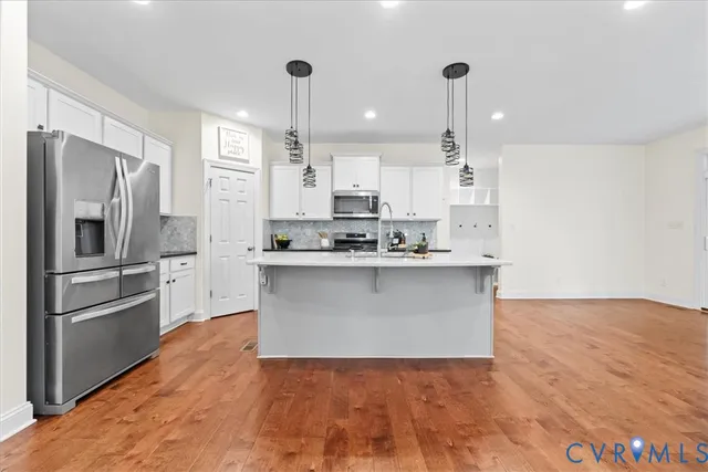 a large kitchen with stainless steel appliances kitchen island granite countertop a stove a refrigerator a sink and a oven