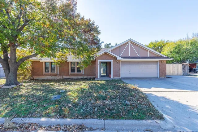 a view of a yard in front of a house with large tree
