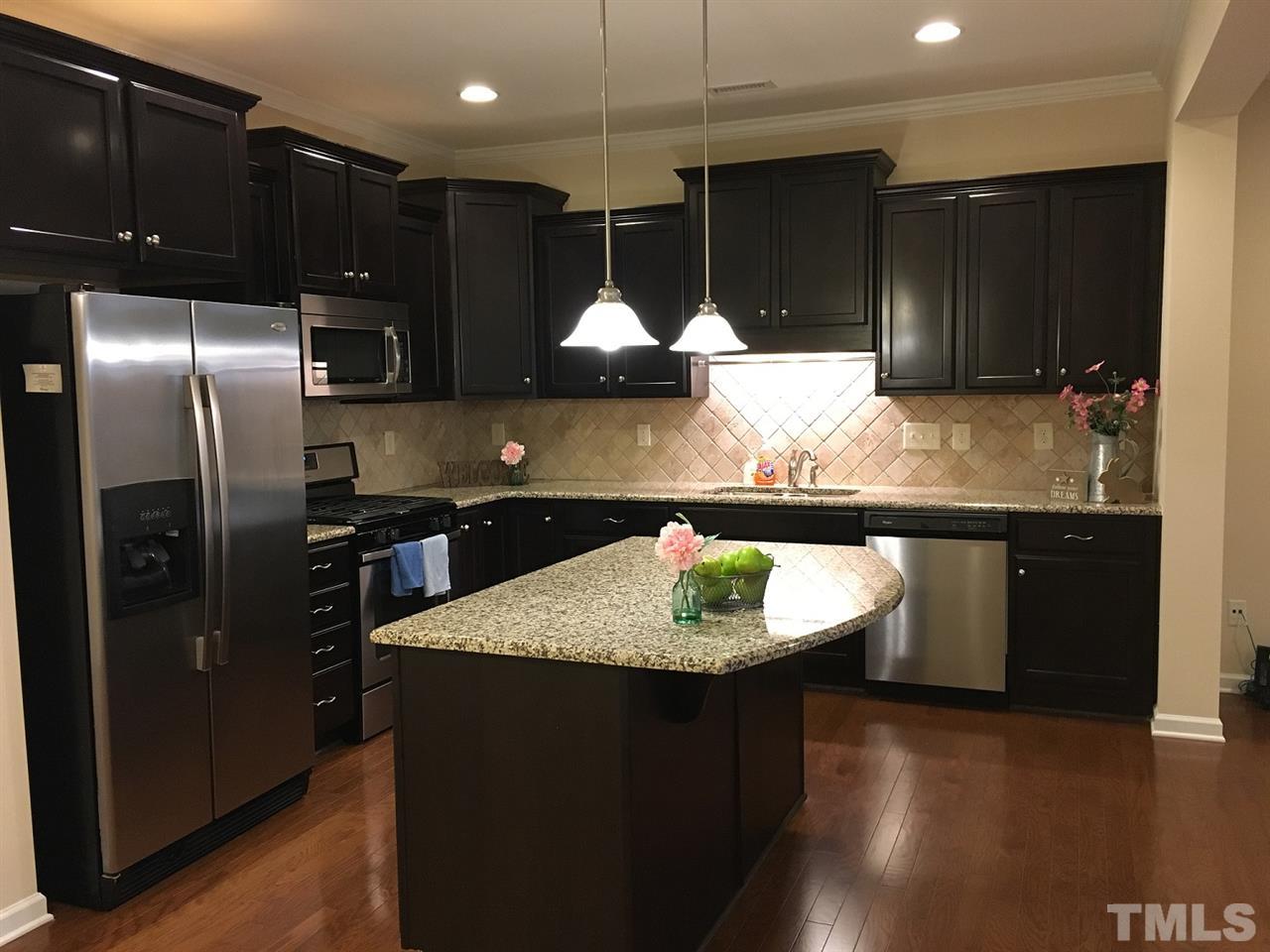 2423 Swans Rest Way Raleigh, NC 27606 - Photo 3 of 25 a kitchen with kitchen island granite countertop a sink and refrigerator