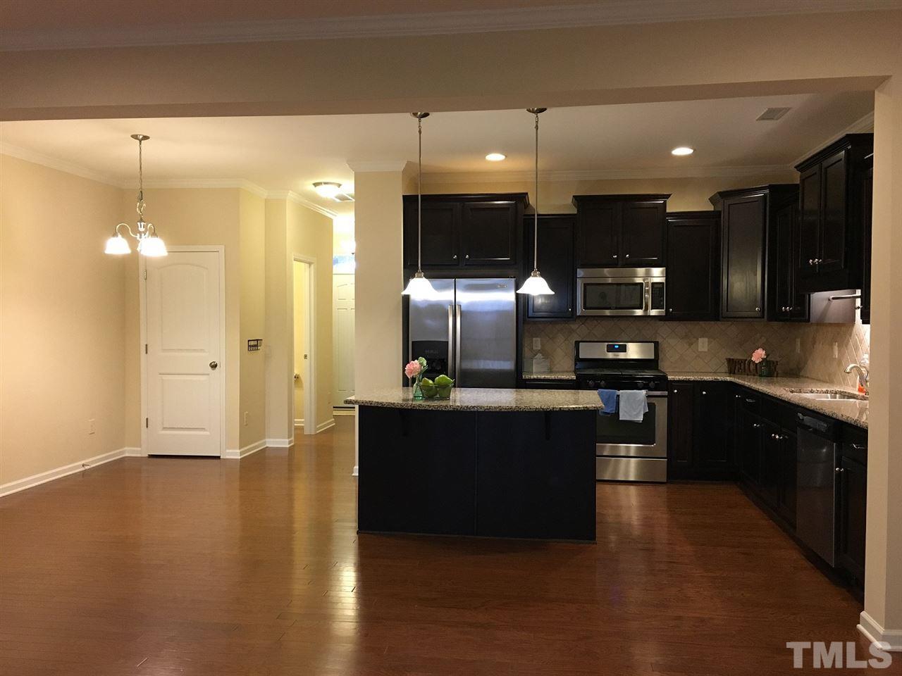 2423 Swans Rest Way Raleigh, NC 27606 - Photo 6 of 25 a kitchen with stainless steel appliances kitchen island granite countertop a stove top oven a sink and a microwave