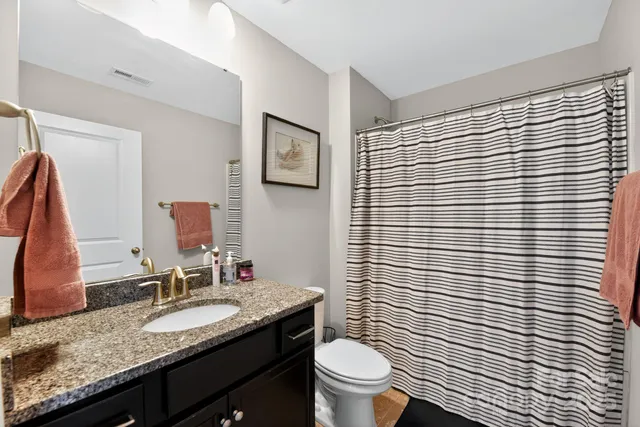 a bathroom with a granite countertop sink toilet and mirror