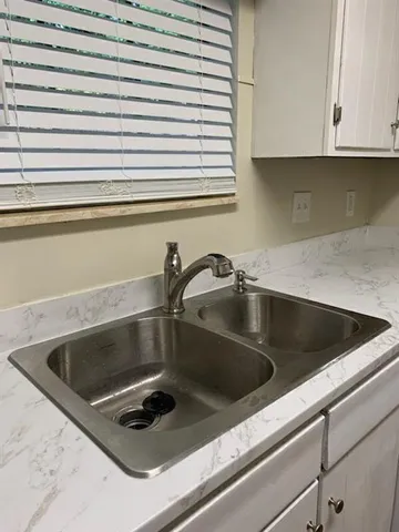 a kitchen with white cabinets and sink