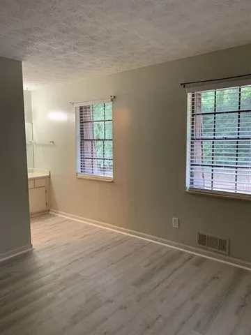 an empty room with wooden floor and windows