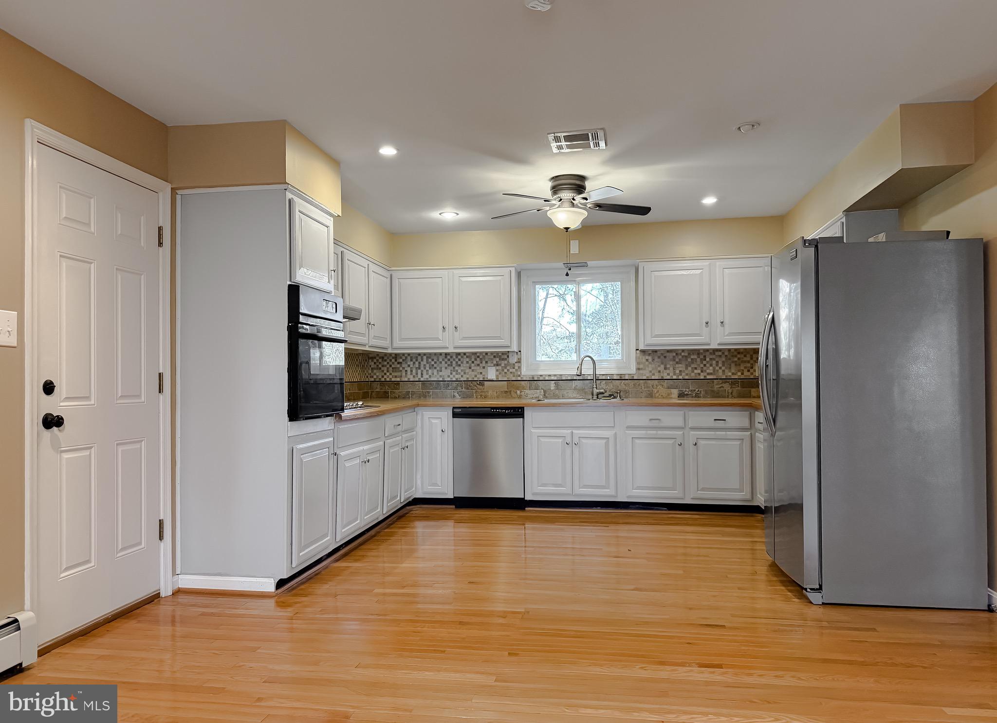 19479 North Snow Hill Manor Road Lexington Park, MD 20653 - Photo 17 of 34 a large kitchen with stainless steel appliances granite countertop a refrigerator a sink dishwasher a oven with white cabinets and wooden floor