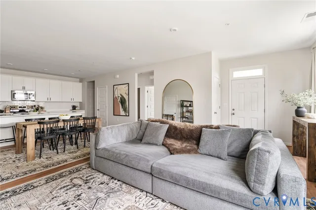 a living room with furniture and a dining table with wooden floor