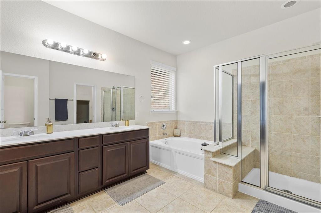 11306 Runnel Ridge Road Manor, TX 78653 - Photo 16 of 26 a spacious bathroom with a double vanity sink a mirror and a bathtub