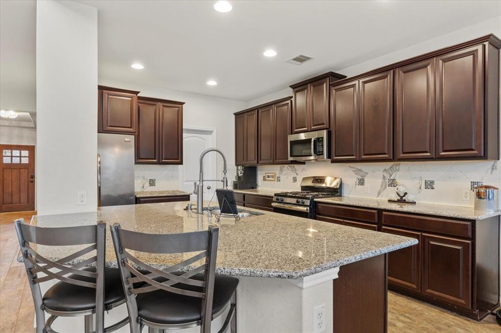 11306 Runnel Ridge Road Manor, TX 78653 - Photo 10 of 26 a kitchen with kitchen island granite countertop a sink stove and microwave