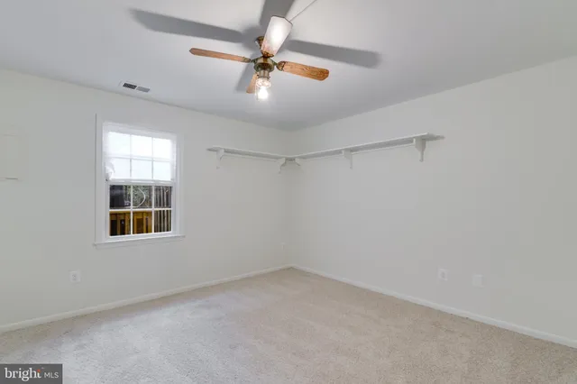 an empty room with a window and a fan