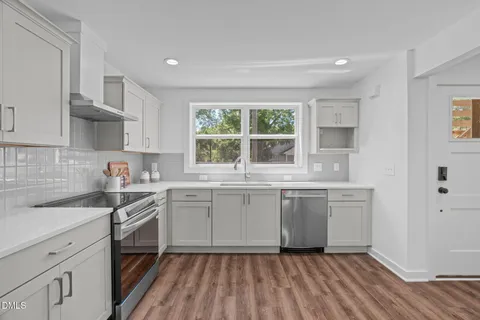 a kitchen with stainless steel appliances granite countertop a stove a sink dishwasher a refrigerator and a oven with wooden floors