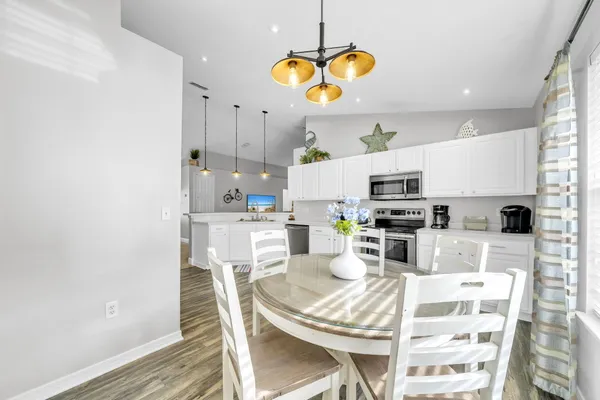 a kitchen with stainless steel appliances a stove a sink dishwasher a refrigerator and white cabinets with wooden floor