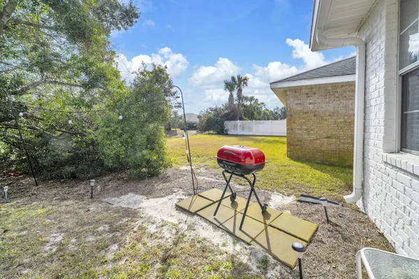 a view of a backyard with table and chairs potted plants and large tree