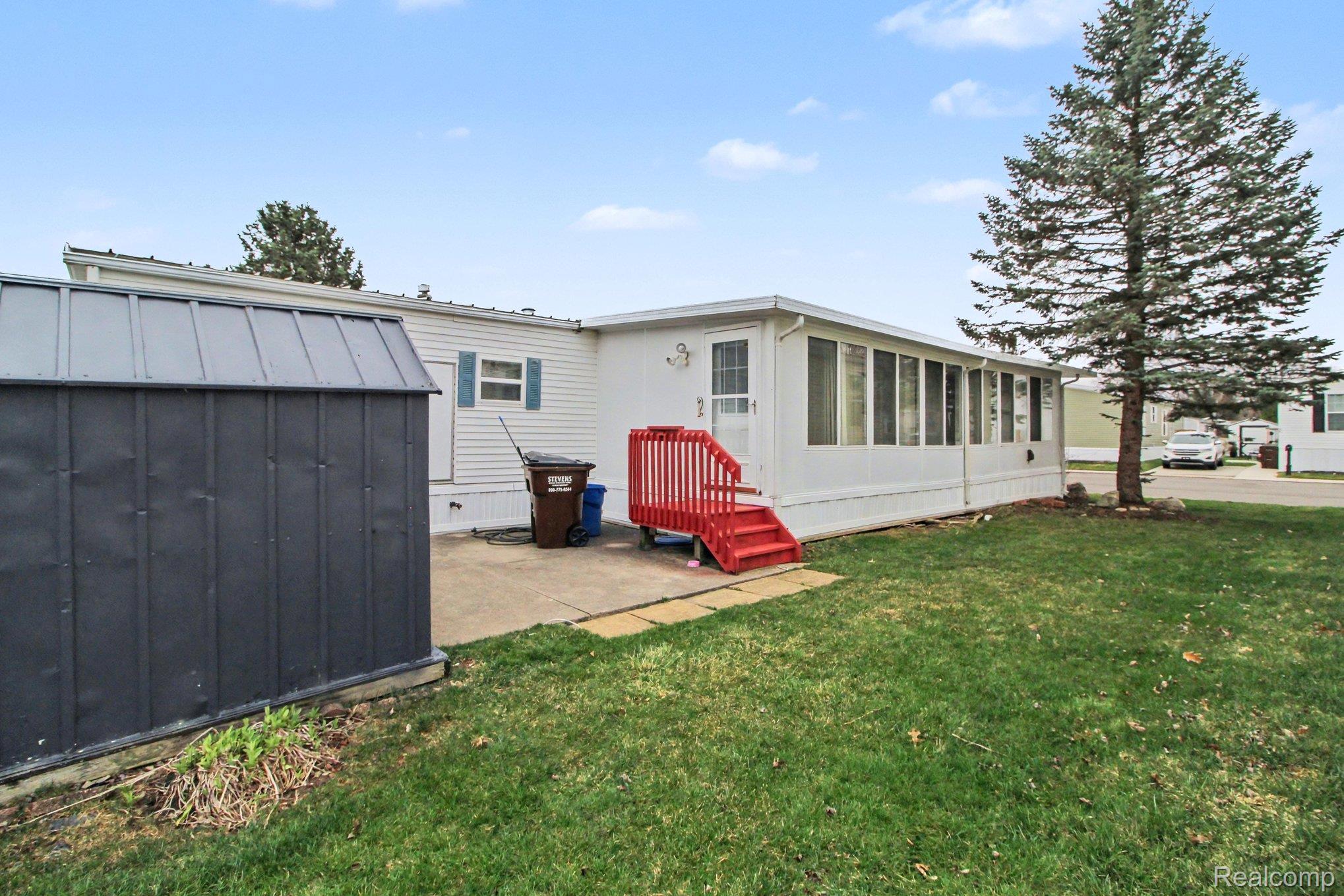 39500 Warren Road, Unit 87 Canton, MI 48187 - Photo 10 of 11 Back of property featuring a lawn, a storage unit, and a patio