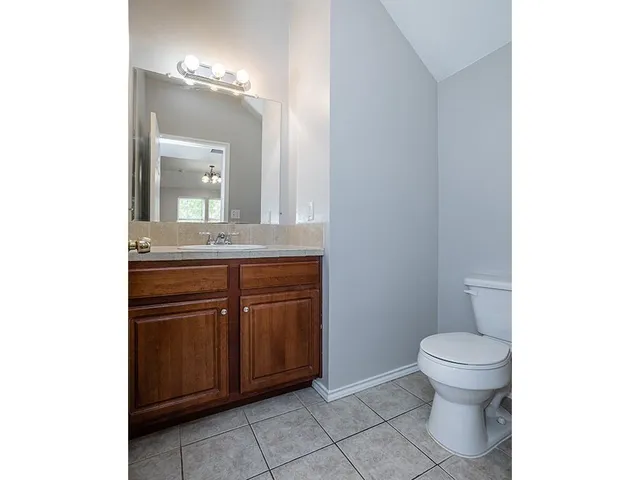 a bathroom with a granite countertop sink and a toilet