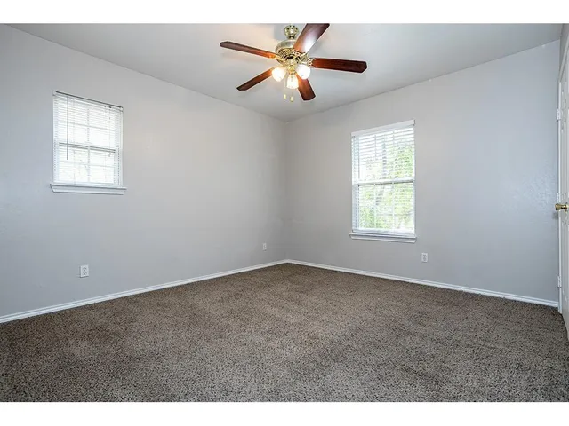 an empty room with windows and fan