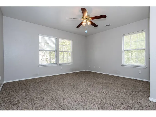 an empty room with windows and fan