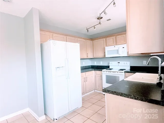 a kitchen with a refrigerator a stove top oven and white cabinets