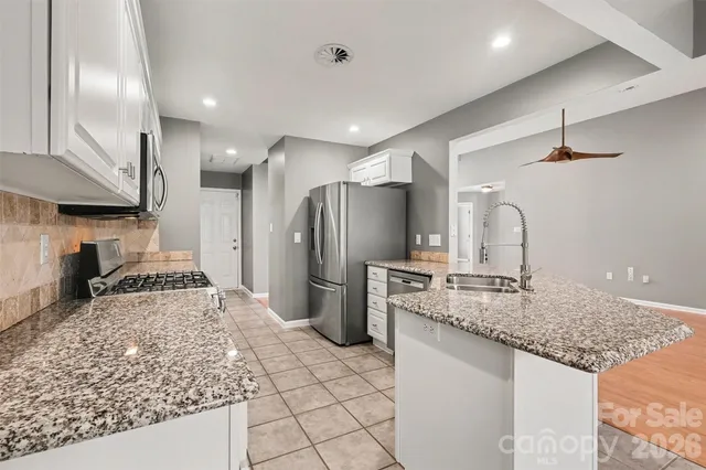 a kitchen with stainless steel appliances granite countertop a sink a stove and a refrigerator