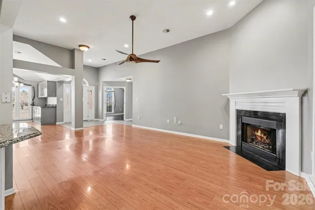 a view of an empty room with wooden floor fireplace and a window