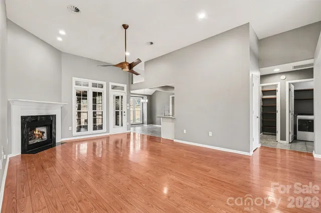 a view of an empty room with wooden floor fireplace and a window