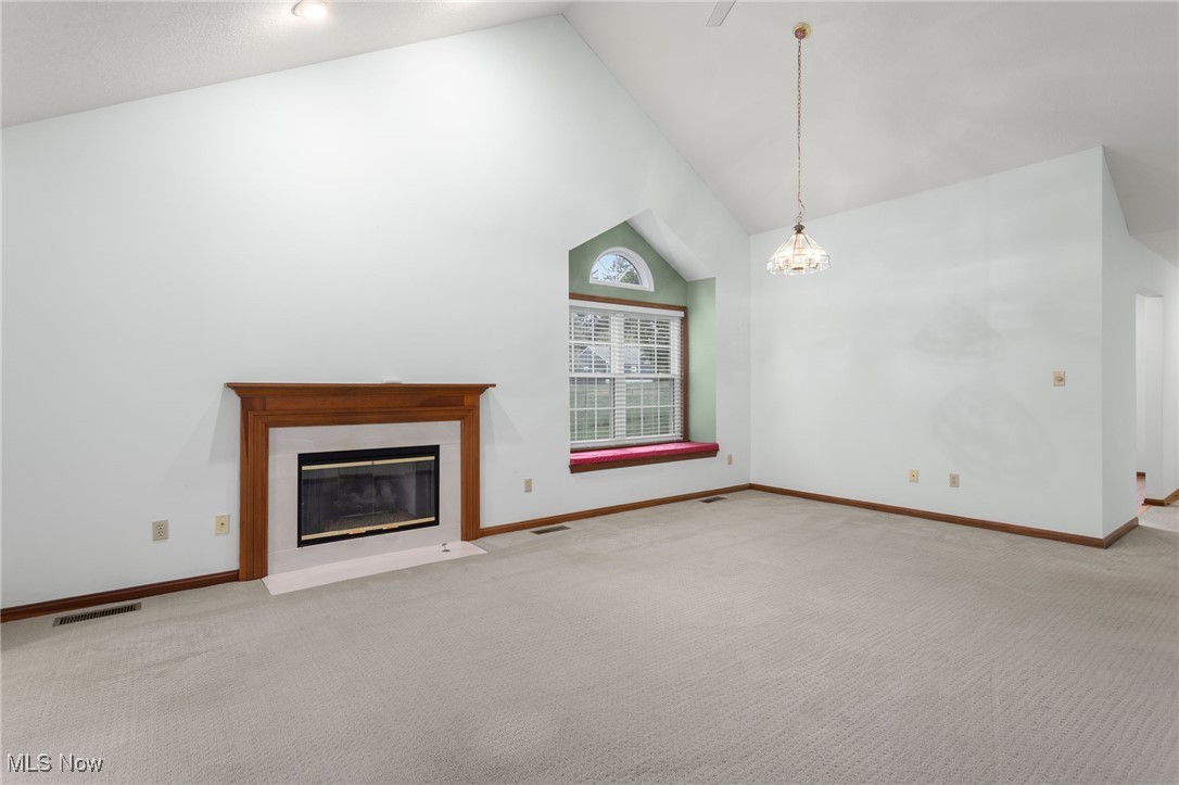 2155 Abbey Road Akron, OH 44312 - Photo 8 of 31 Unfurnished living room with high vaulted ceiling, carpet, and a fireplace with flush hearth