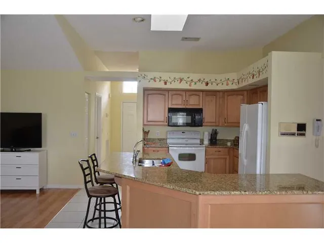 a kitchen with stainless steel appliances kitchen island granite countertop a refrigerator and a stove top oven