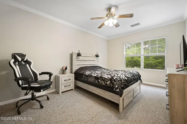 a bedroom with a bed a chandelier and a dresser