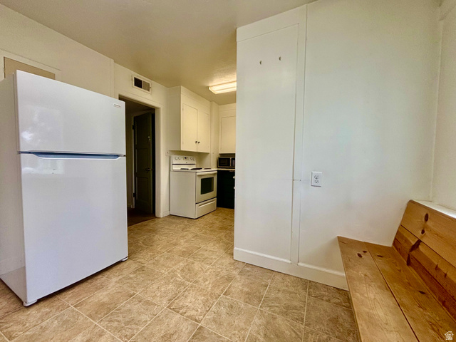 704 North 200 East Logan, UT 84321 - Photo 5 of 24 Kitchen with white appliances, white cabinetry, and light countertops