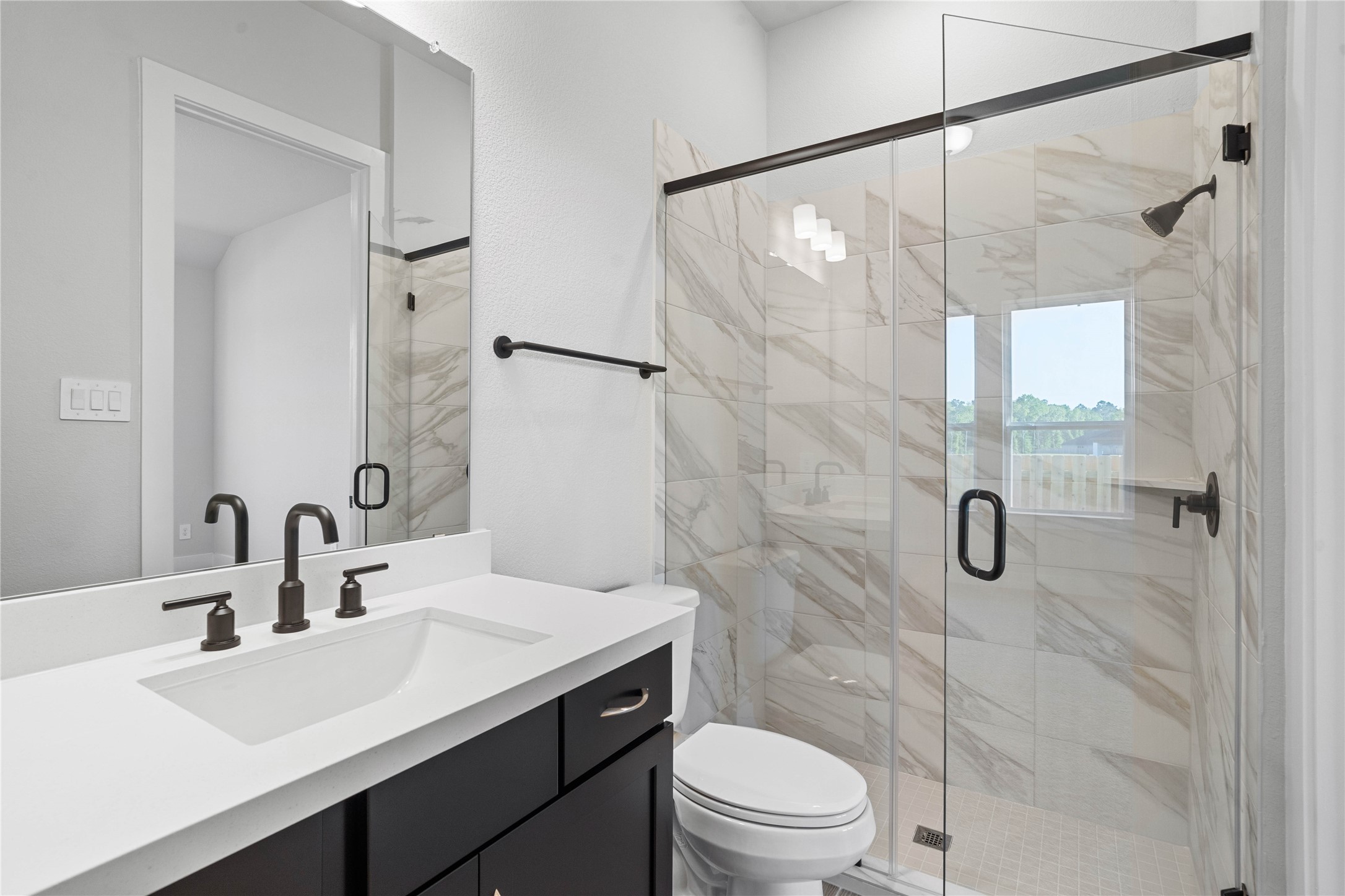 2114 Rowl Street Montgomery, TX 77316 - Photo 16 of 50 This ensuite bathroom features a large glass framed walk in shower, and single vanity with overhead lighting and large mirror.