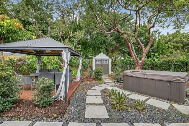 a backyard of a house with table and chairs potted plants and large tree